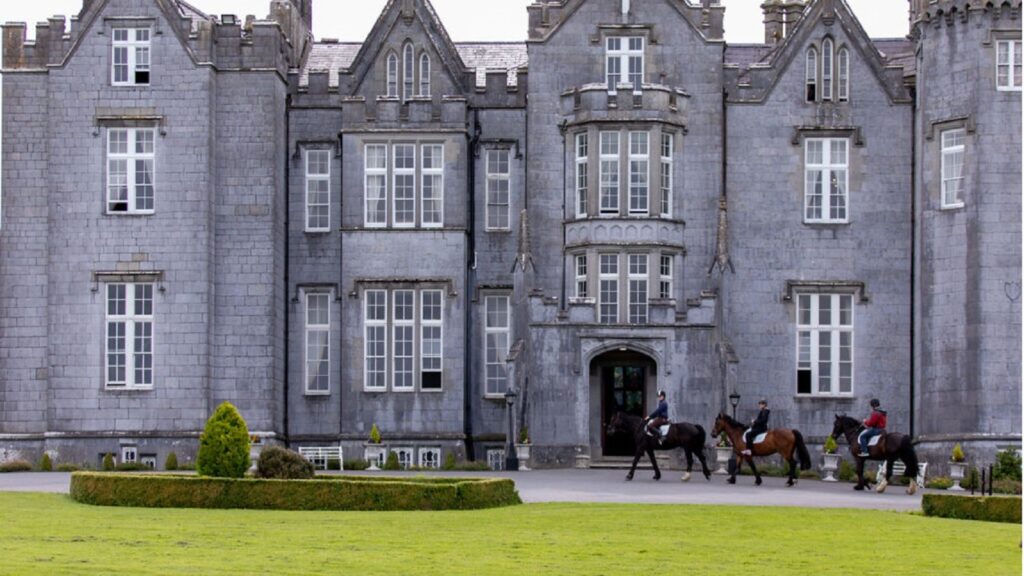 Photo of Kinnitty Castle with three men on horseback riding to the front door.