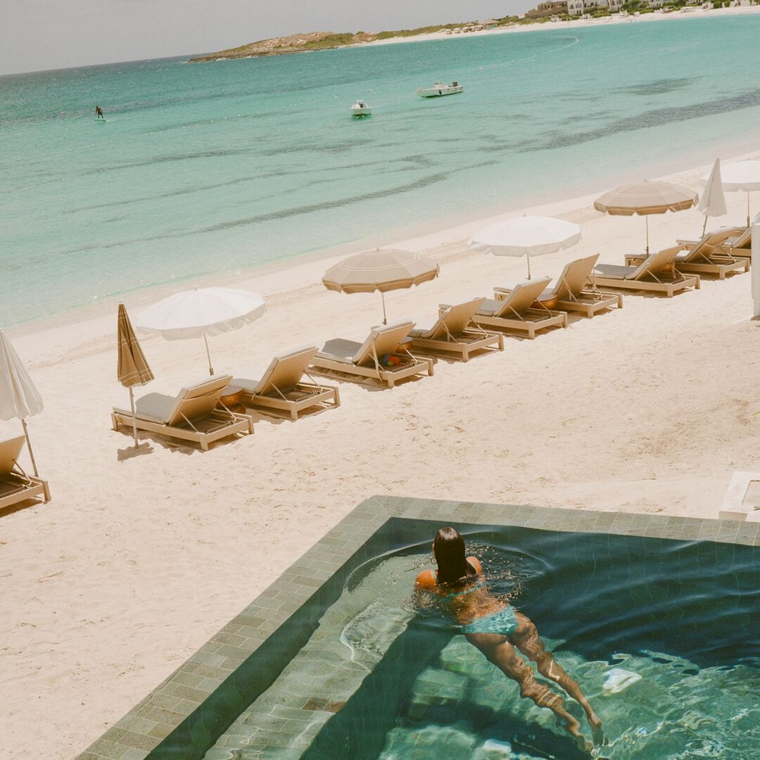 Guest relaxing in a private plunge pool at Cap Juluca, Anguilla, overlooking white-sand beach and turquoise Caribbean water during off-season travel.