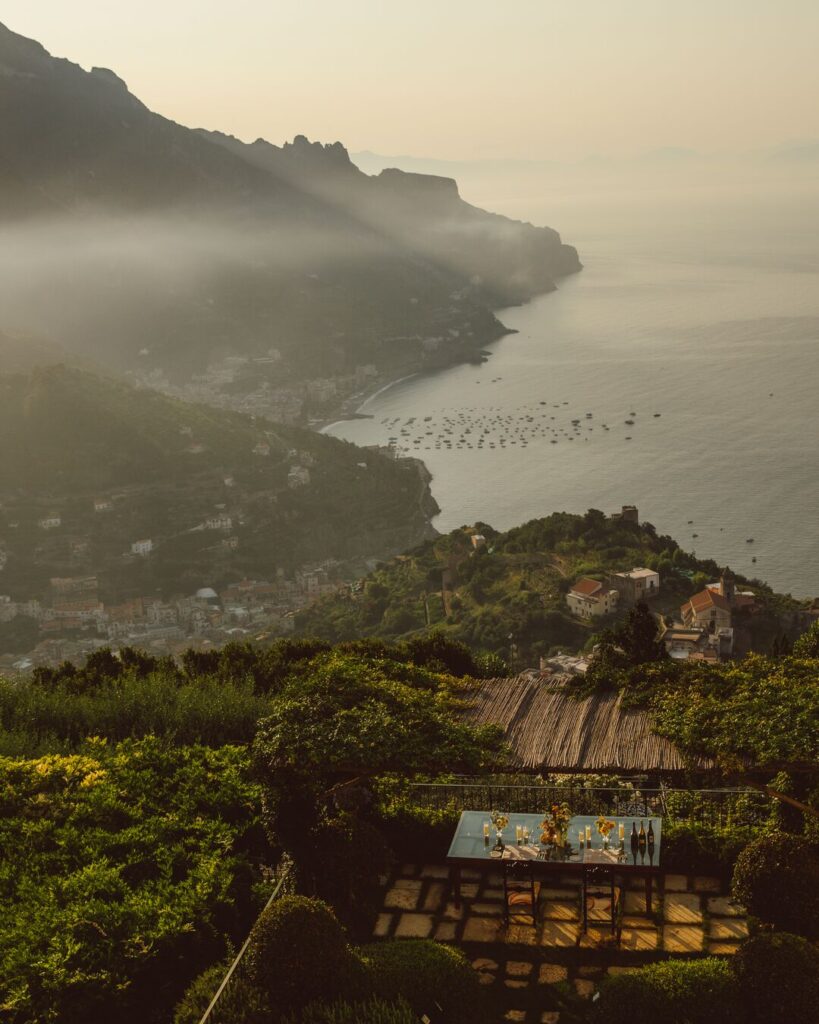A view of the Amalfi Coast from Ravello, showing terraced hills, coastline, and boats in the Tyrrhenian Sea.