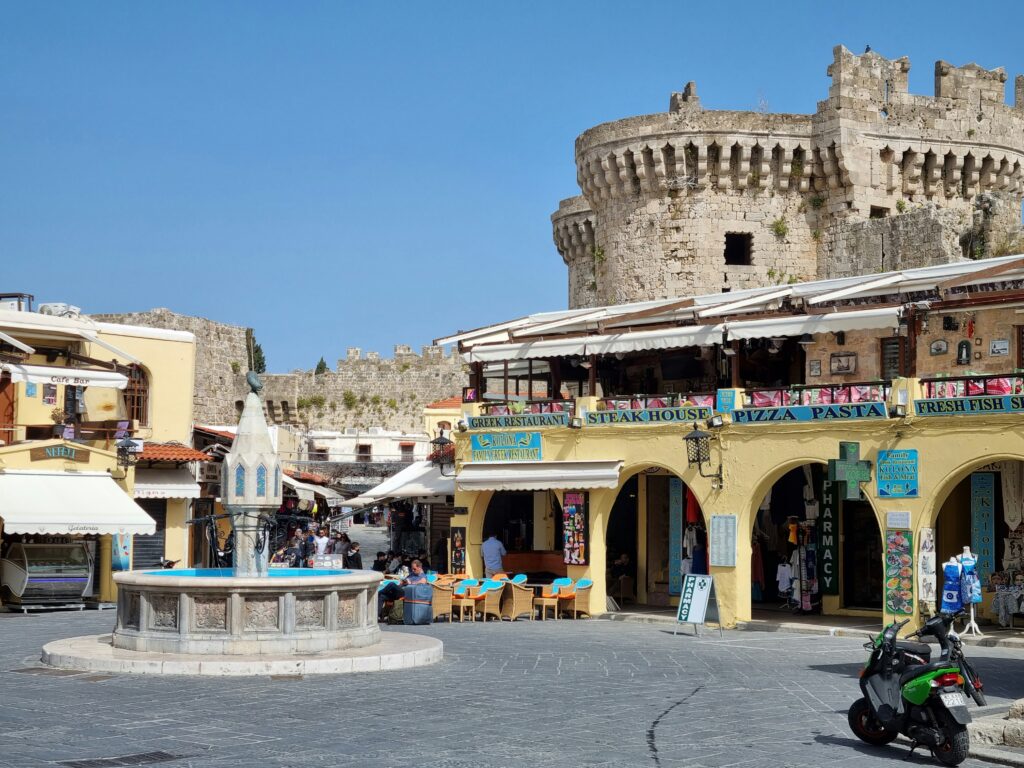 Rhodes Old Town square with medieval stone walls and shops.