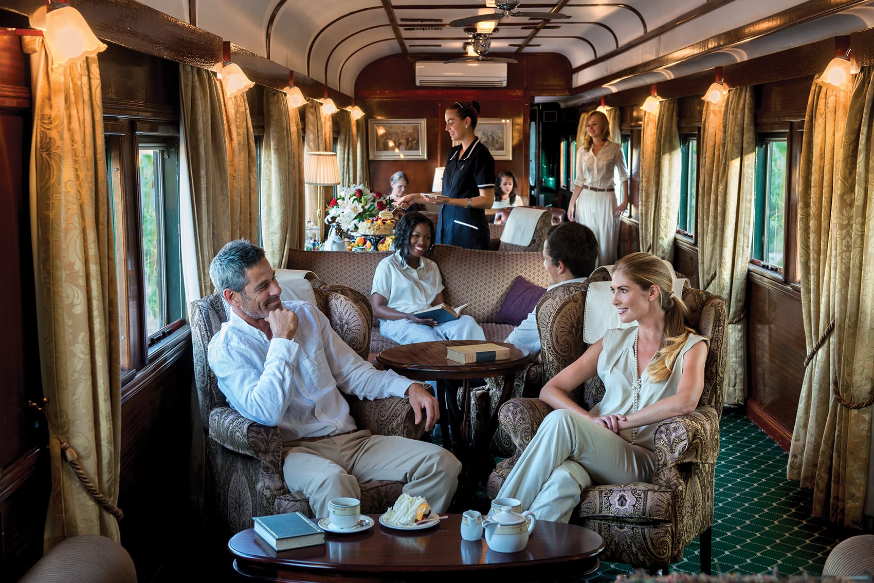 Guests relaxing in the Rovos Rail lounge car with attentive service on board